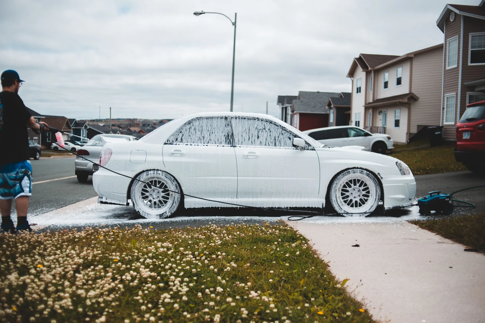 A vehicle receiving an exterior foam wash in a driveway
